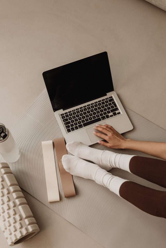 Lady exercising to reinvent herself using a place mat, laptop, foam roller, and computer

