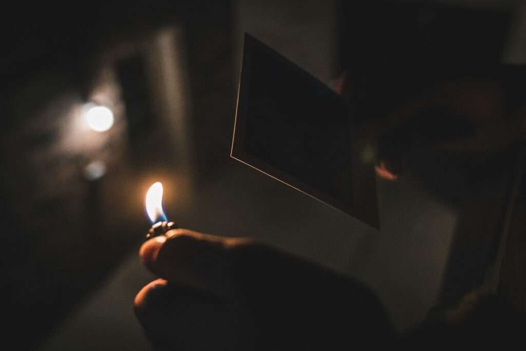 Someone holding a lighter and photo to reinvent themselves
