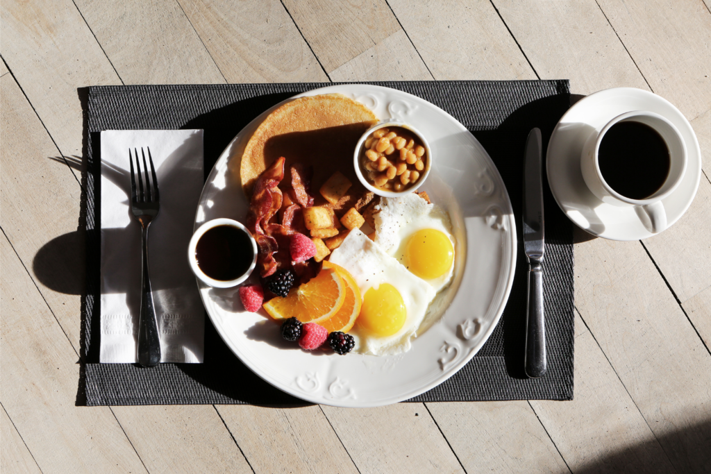 Close up picture of pancake, beans, eggs, fruits, syrup, and coffee
