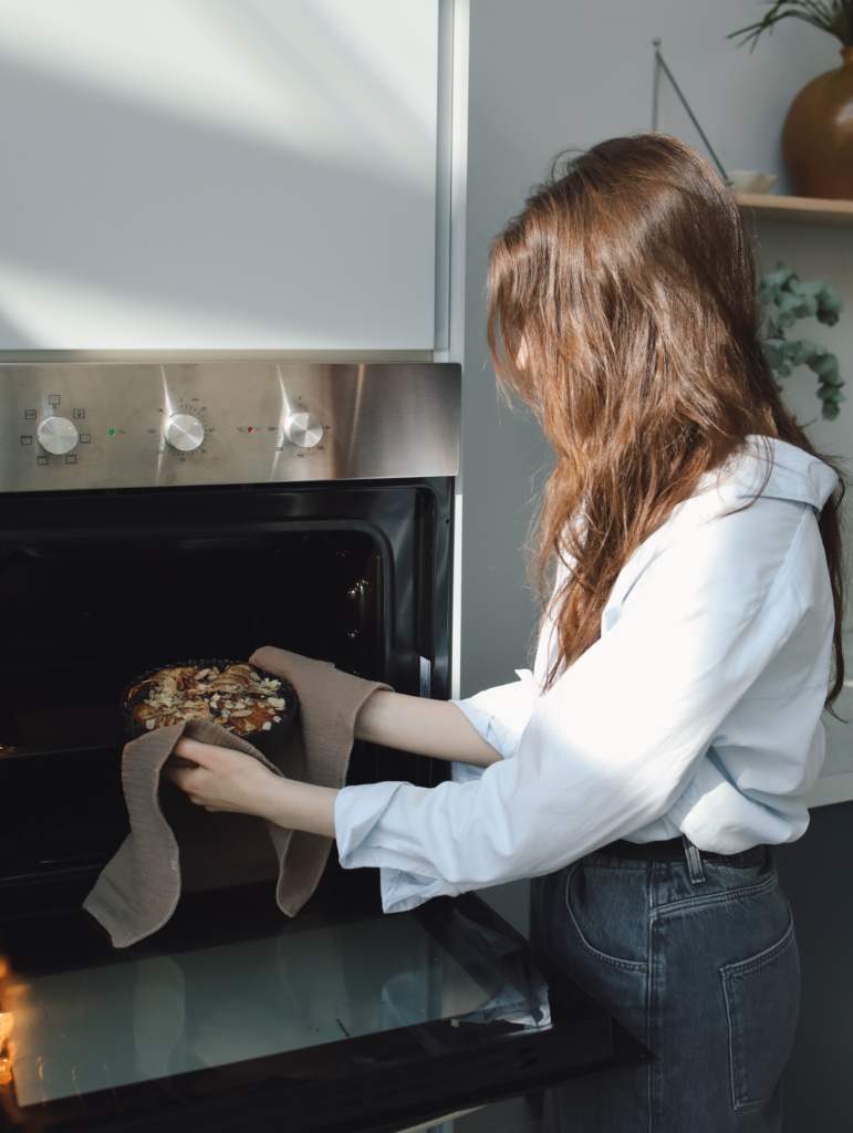 A woman putting food in the oven.