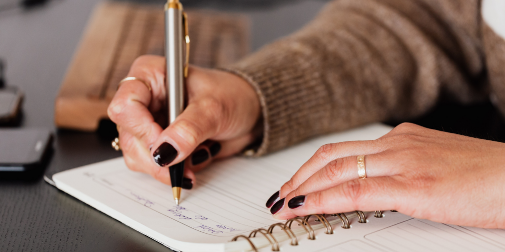 Build a healthy relationship with food by planning and preparing meals. A woman writing in a spiral notebook.