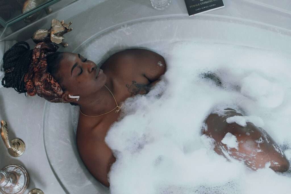 Prioritize self-care while reinventing yourself professionally. Image of a woman lying in a bubble bath.