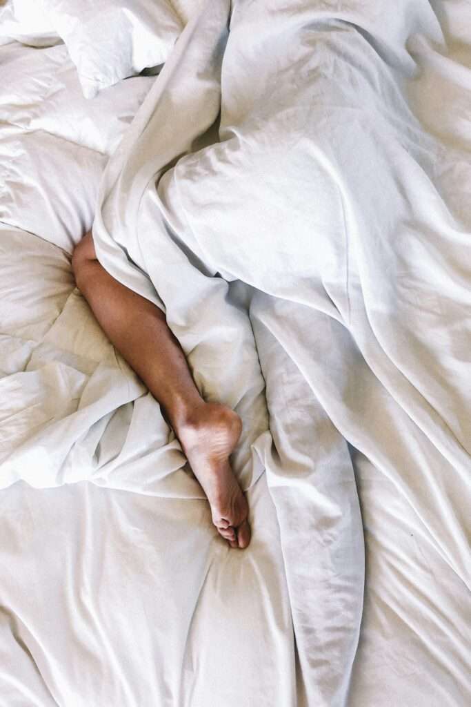 Women wrapped up in a white duvet sleeping.