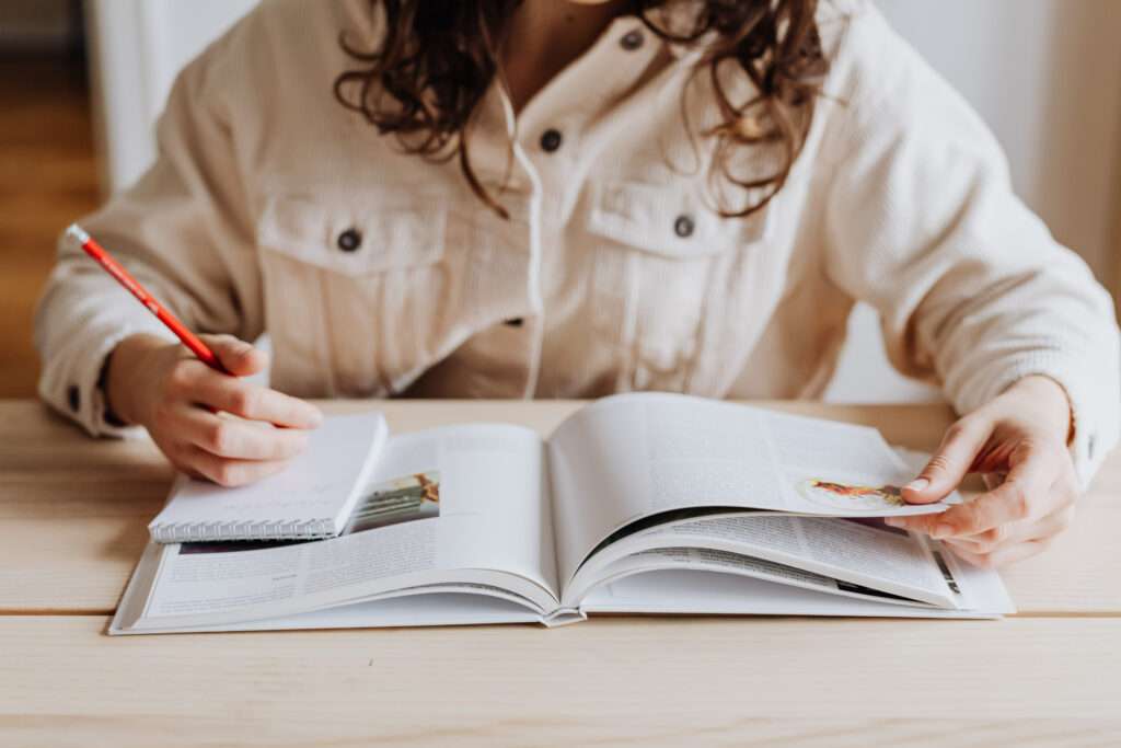 Image of a woman sitting to a table and reading a textbook.