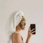 How to reinvent yourself physically. Woman taking an image of herself while having on a facial mask and towel wrap on her head