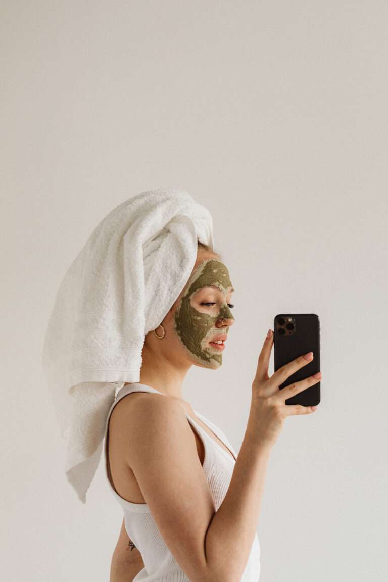 How to reinvent yourself physically. Woman taking an image of herself while having on a facial mask and towel wrap on her head