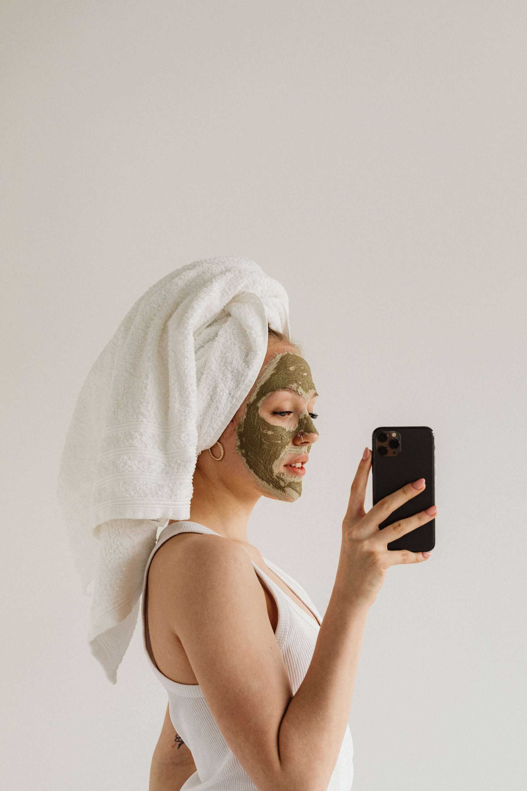 How to reinvent yourself physically. Woman taking an image of herself while having on a facial mask and towel wrap on her head