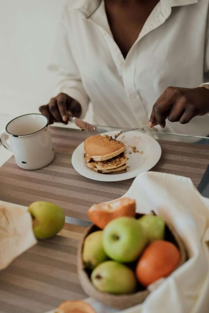 Repairing relationship with food by practicing mindful eating. A woman sitting at the table eating breakfast.