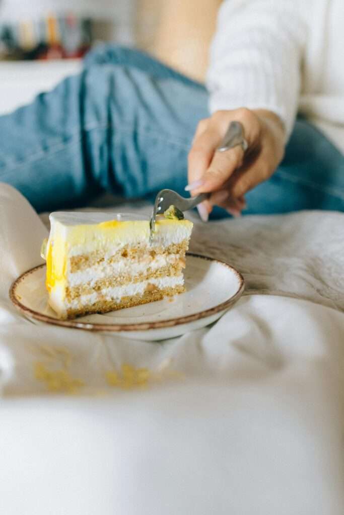 Heal relationship with food by honoring your cravings without overindulging. A woman eating a slice of cake.