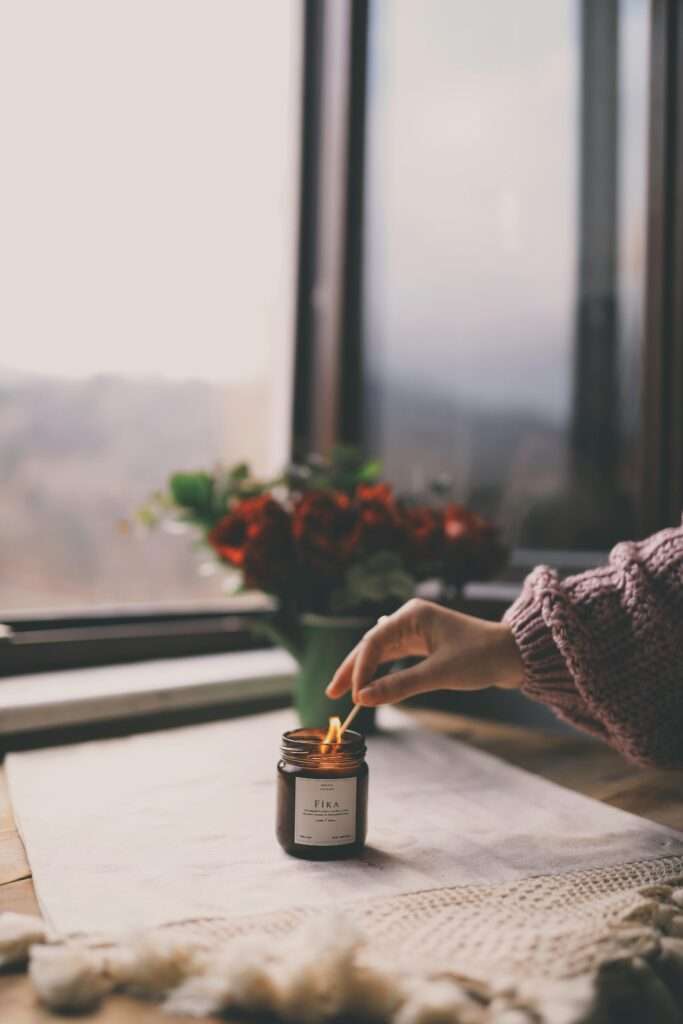 Woman lighting a candle in the front of the window.