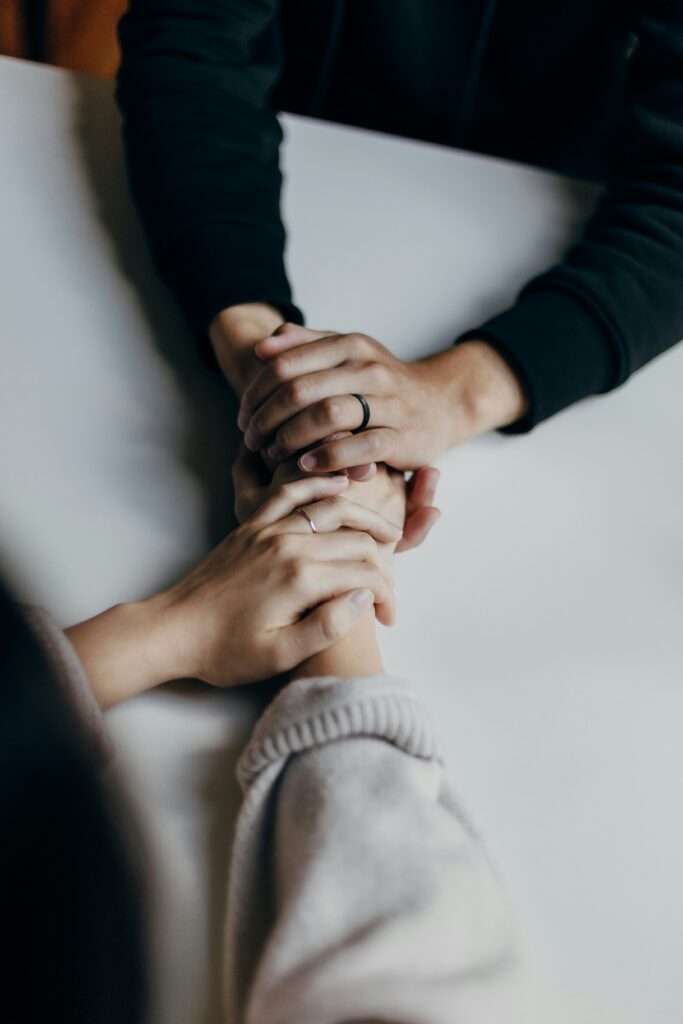 How to reinvent your relationships by having open and honest conversations. A married couple holding each other hands while sitting at a table.