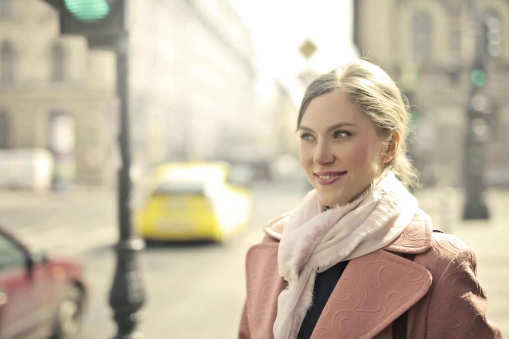 A woman smiling on the street.