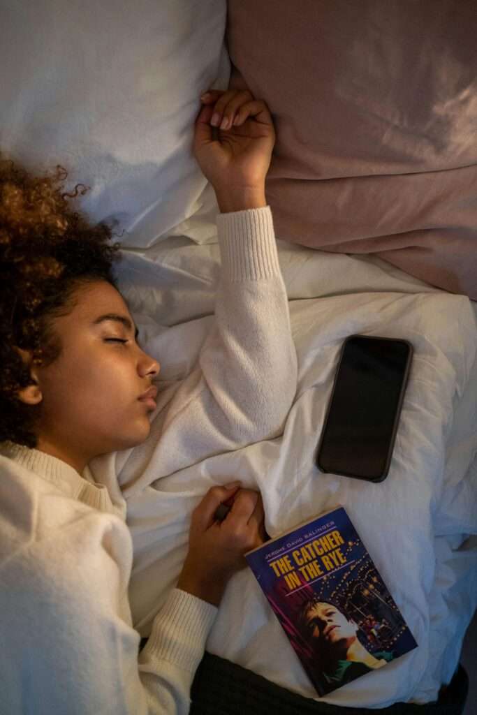 A woman sleeping with a phone and book beside her