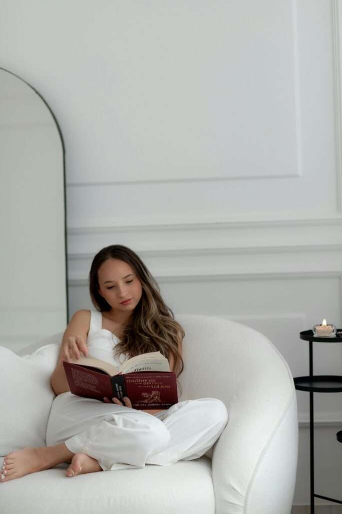 A woman sitting on white sofa and reading a book