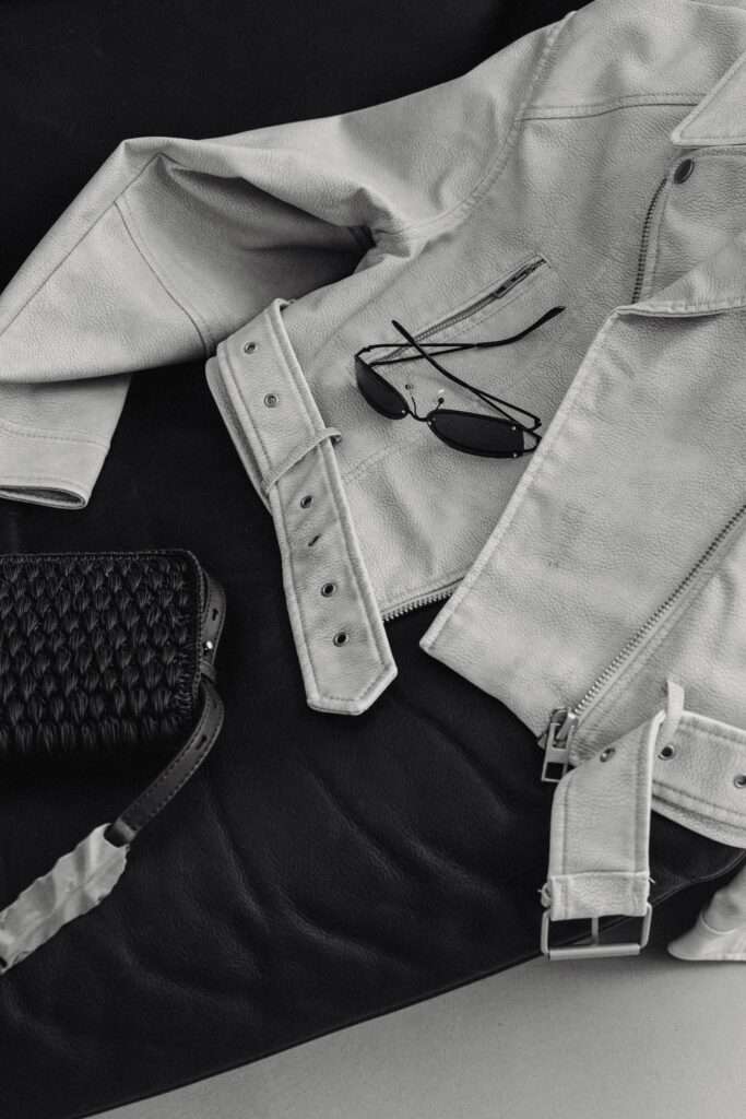 Image of a white leather jacket, glasses, and purse on a couch