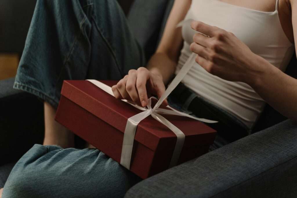 A woman opening a present with a white bow on it