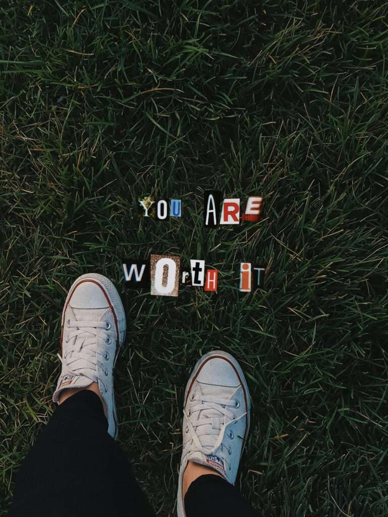 An image of a woman standing in grass wearing Converse sneakers
