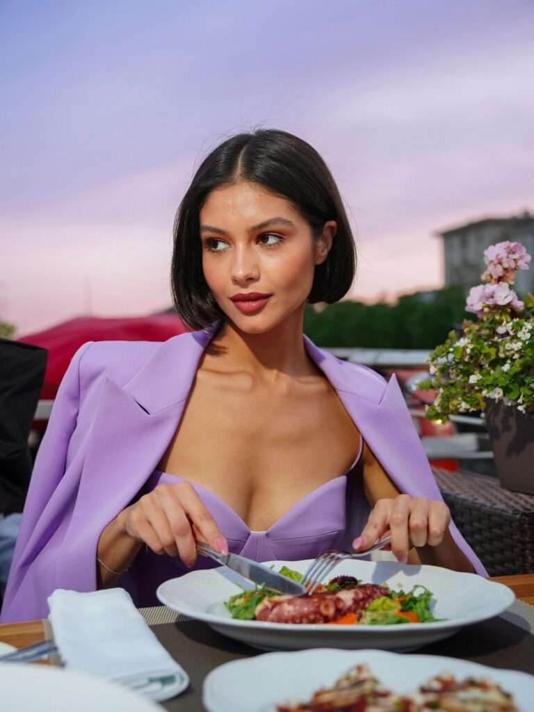 A woman wearing a purple suit and having dinner at a restaurant