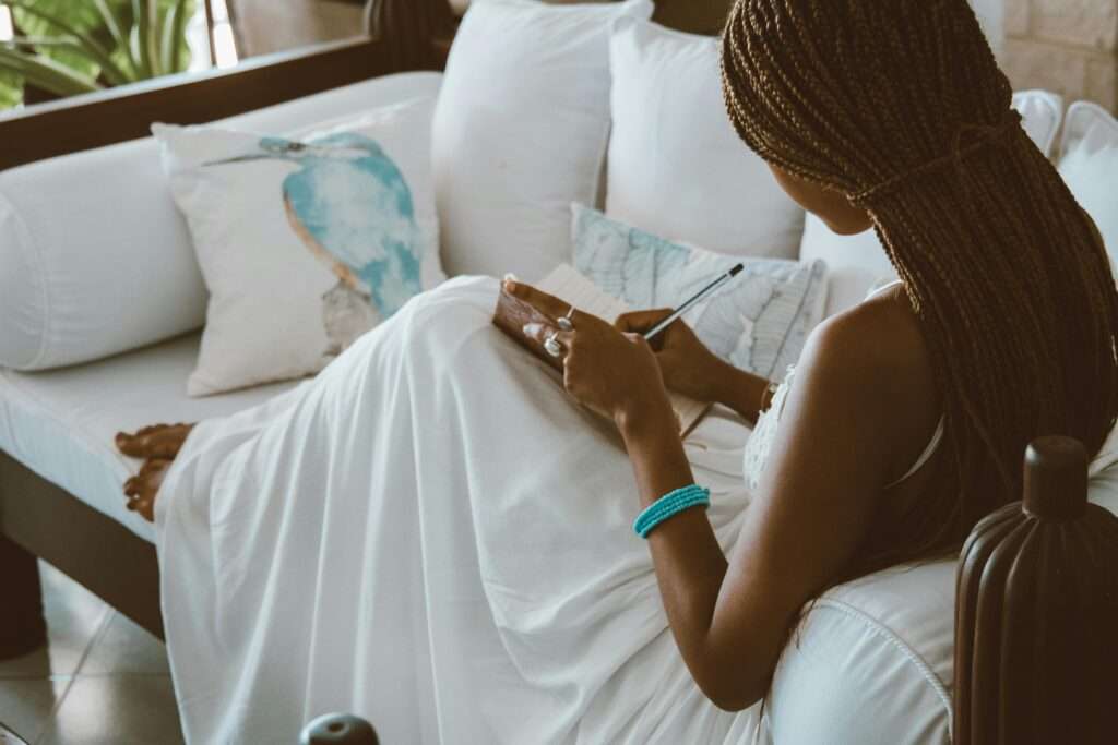 Woman writing in her journal while sitting on the couch.