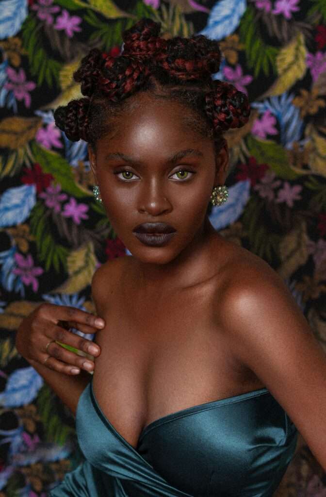 An image of a woman posing in front of a floral background

