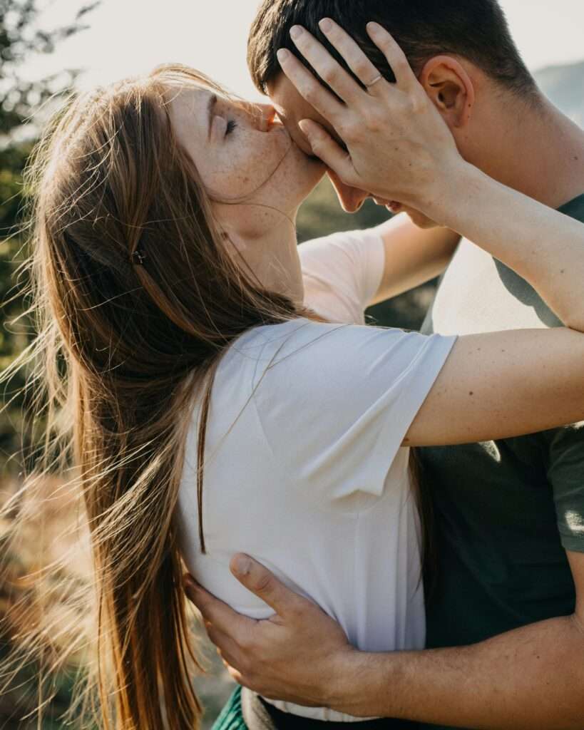 A close up image of a woman kissing the forehead of a man.
