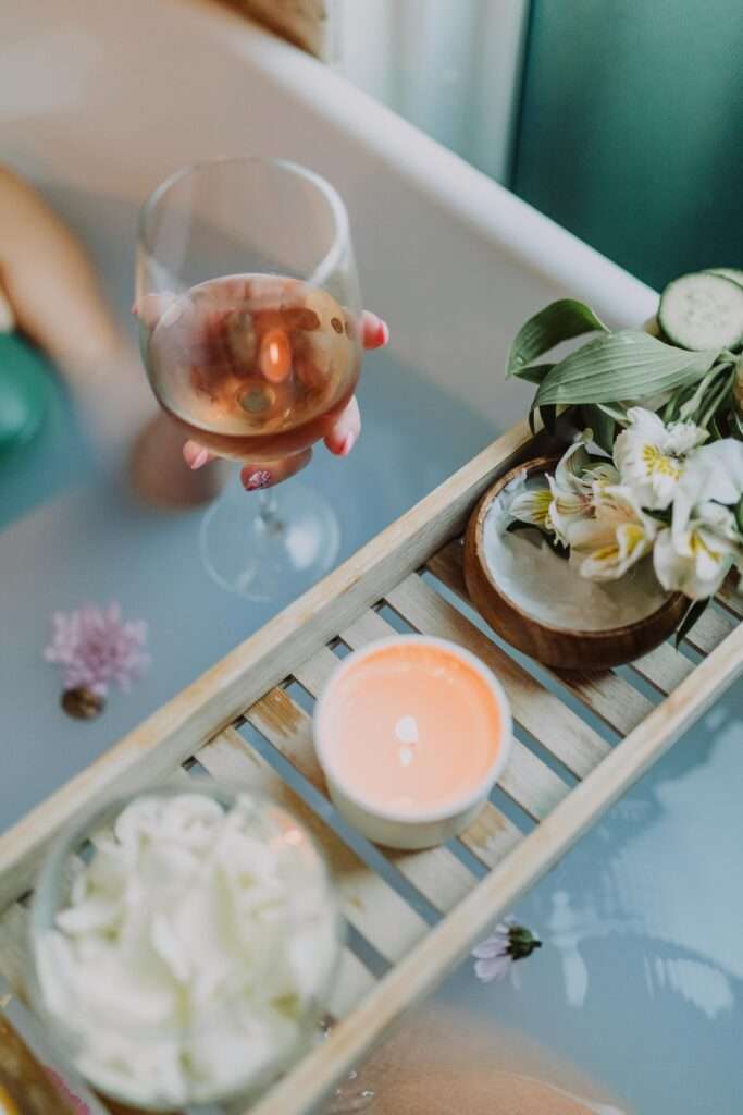 An up close image of a woman taking a bath while sipping wine.
