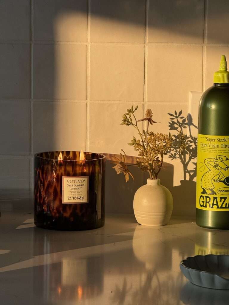 Image of a candle, vase, and olive oil on a counter.