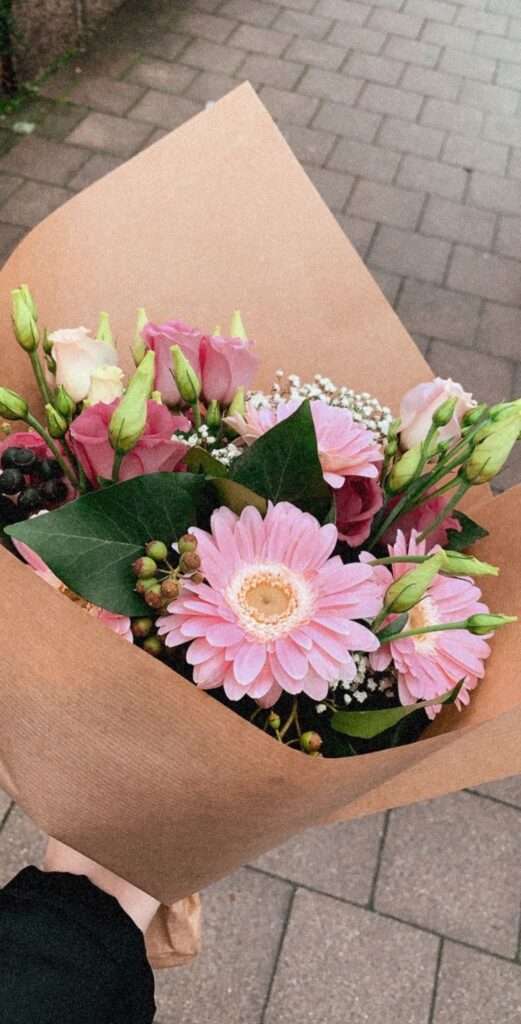 Image of a woman holding a bouquet of different shades of pink flowers.