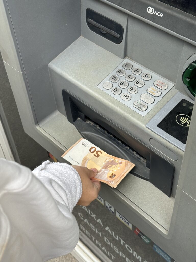 A close-up image of a woman putting money into an atm machine.
