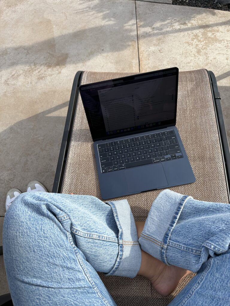 Image of a woman sitting on a lounge chair whilst on her laptop.