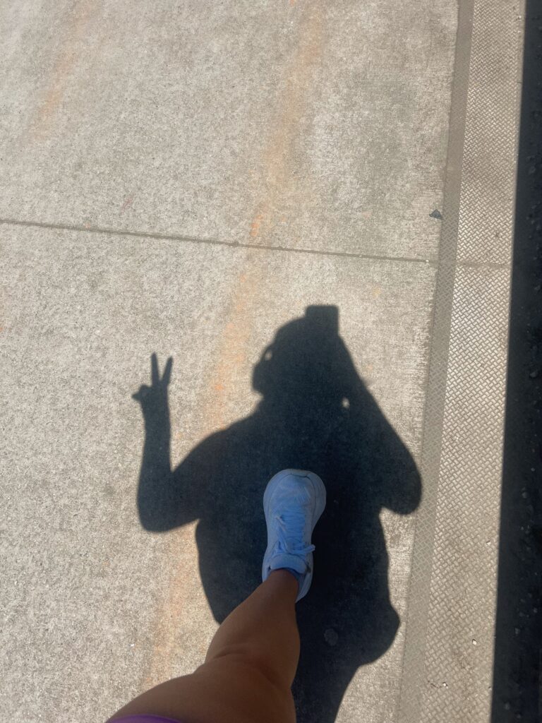 Image of a woman taking a selfie of her shadow whilst walking.